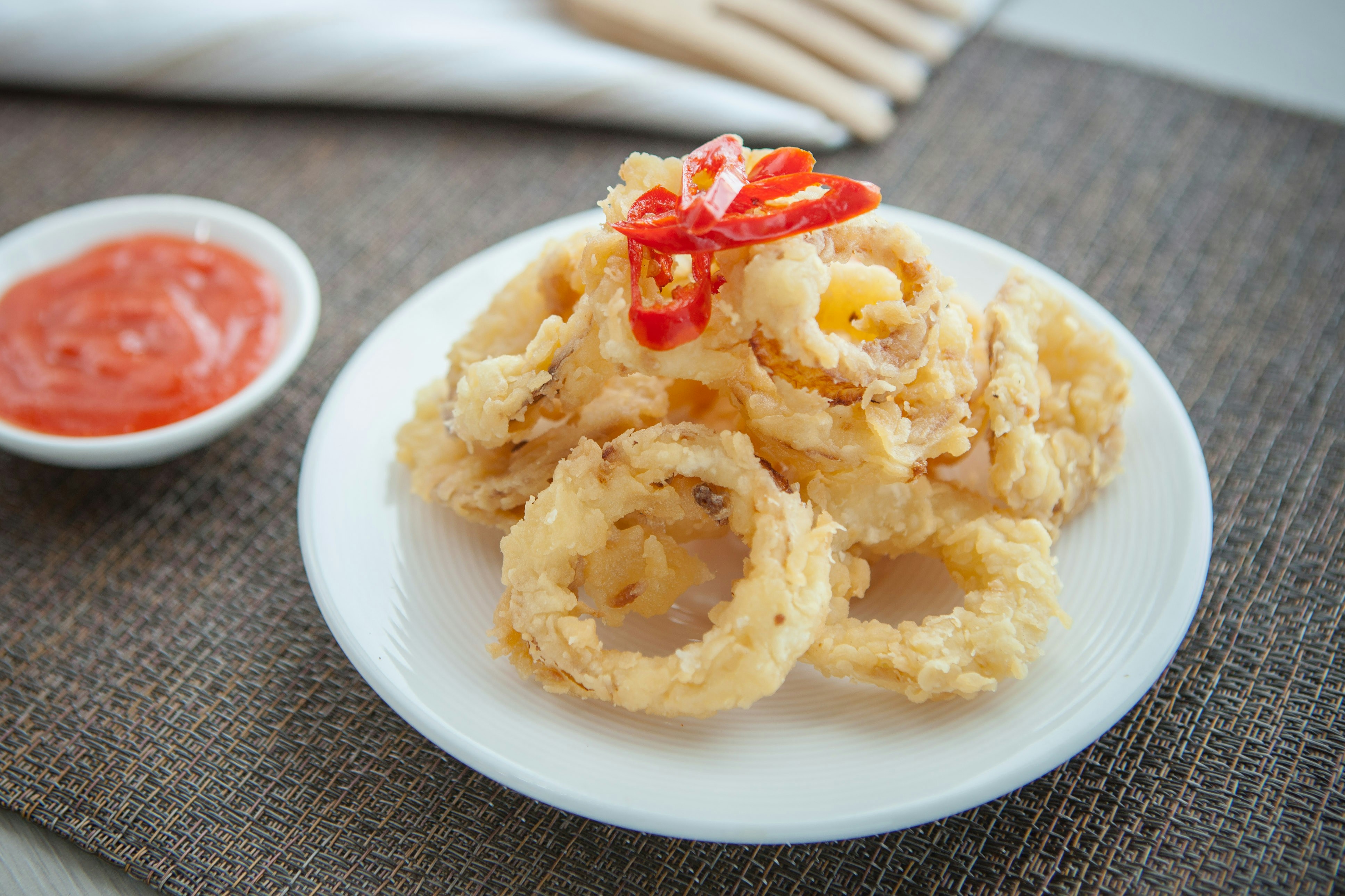 a white plate with onion rings and sauce