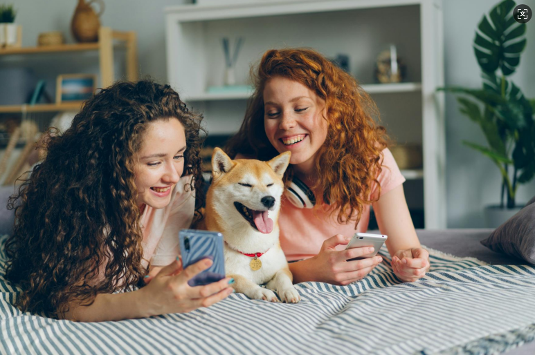two women laying on a bed with a dog