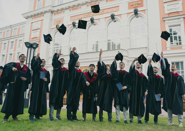 a group of people in graduation gowns holding caps up