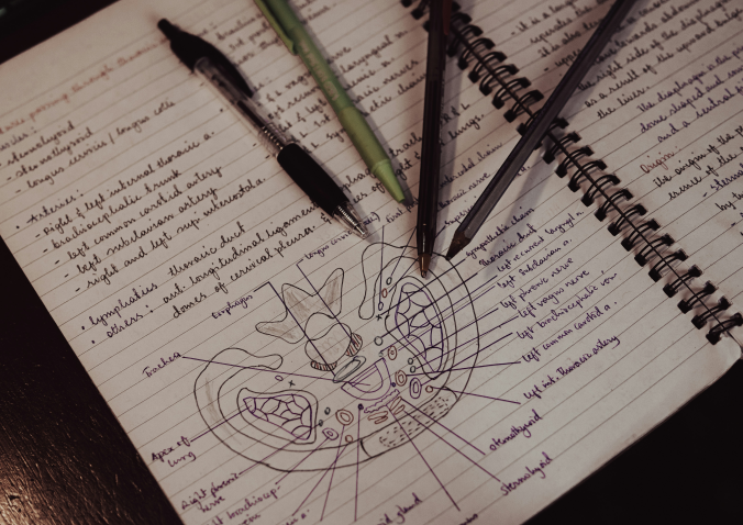 notebook with medical course note on it and pens