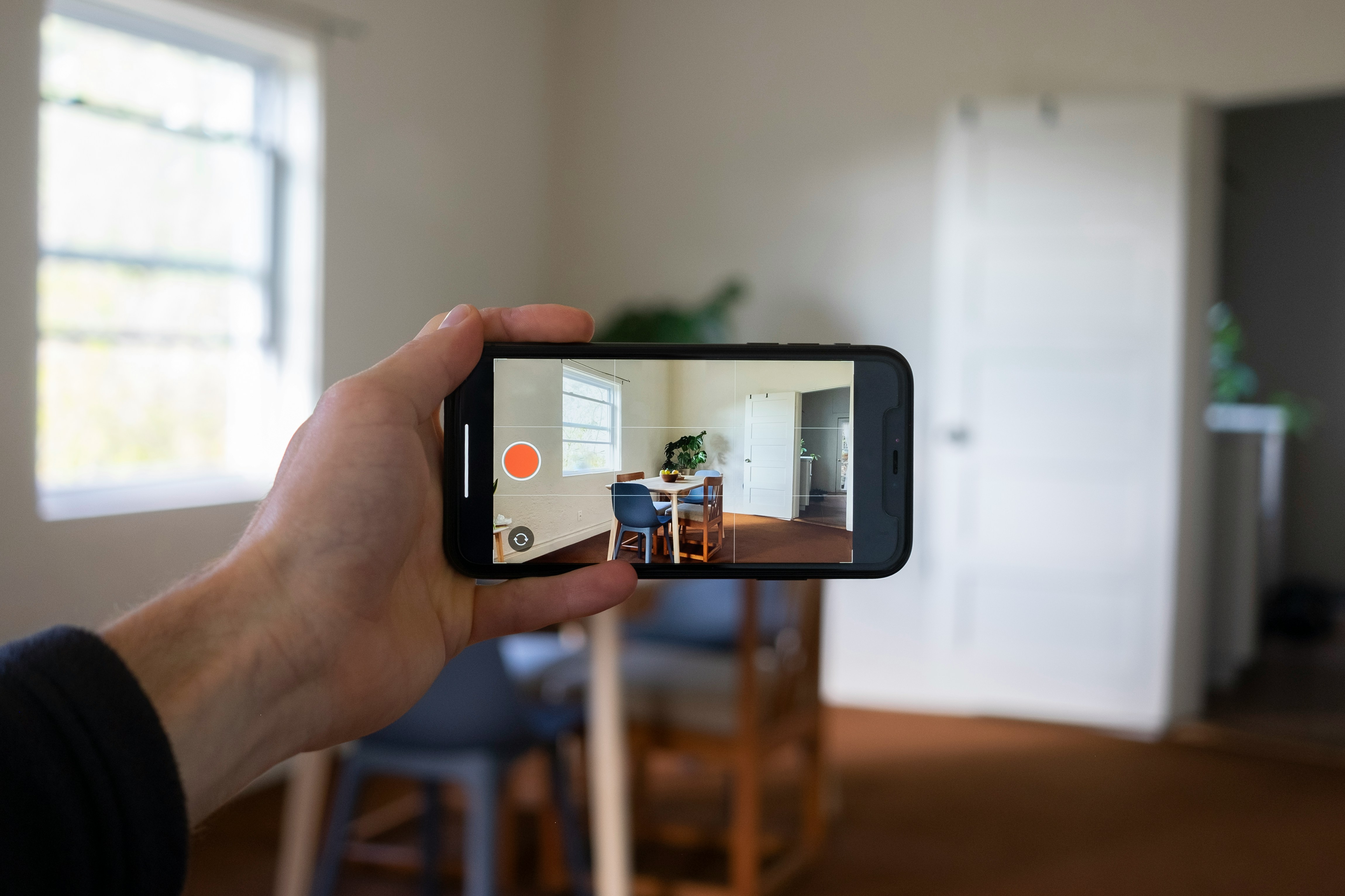 a person holding a smart phone taking a picture of a table in a room