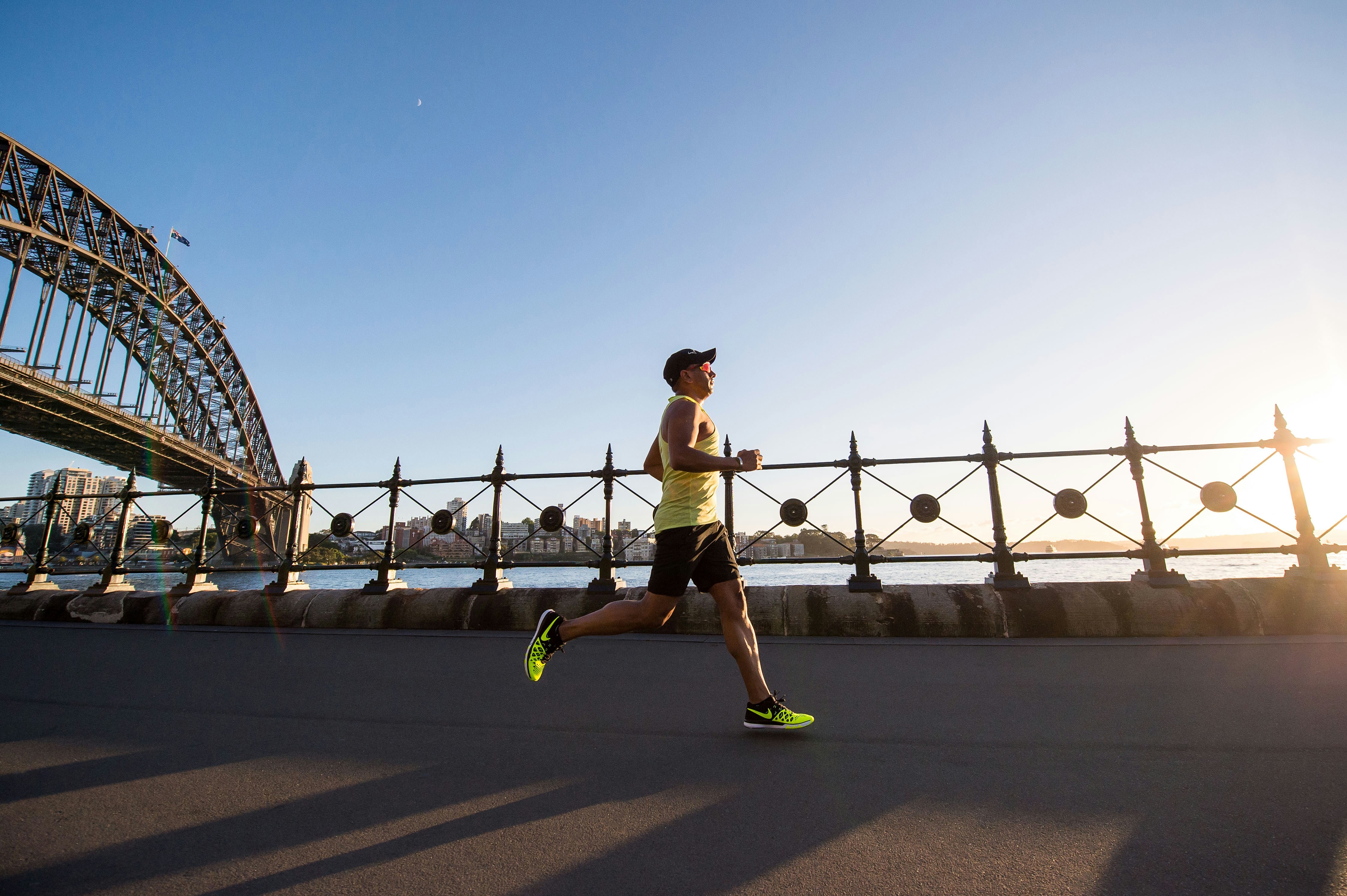 a man in yellow tank top running by shore