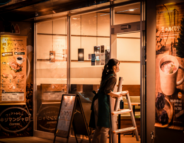a woman standing outside of a coffee shop at night