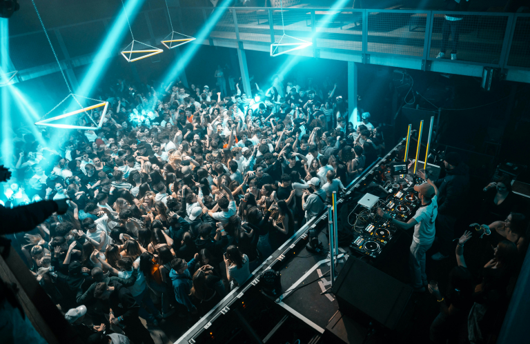 a crowd of people standing around a DJ booth